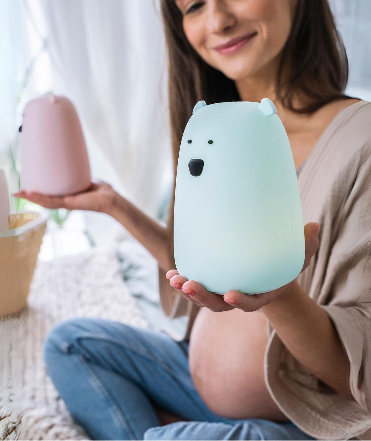 A woman holding a white silicone lamp in the shape of a teddy bear with charming features like small ears and a round belly. Ideal for bedtime routines and providing a sense of security for children.