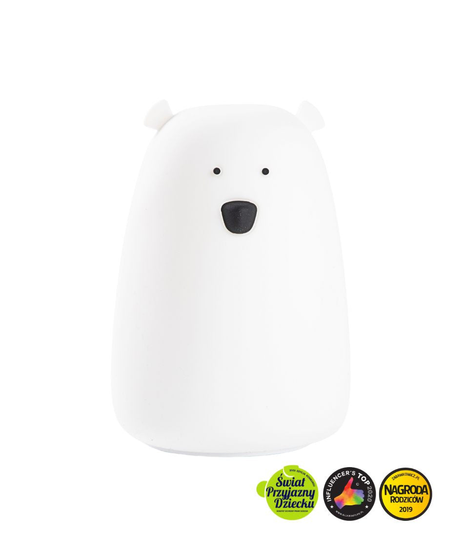 A white silicone lamp shaped like a teddy bear with black eyes and nose, from Rabbit & Friends. Soft, touch-responsive, and portable for bedtime routines and comforting light.