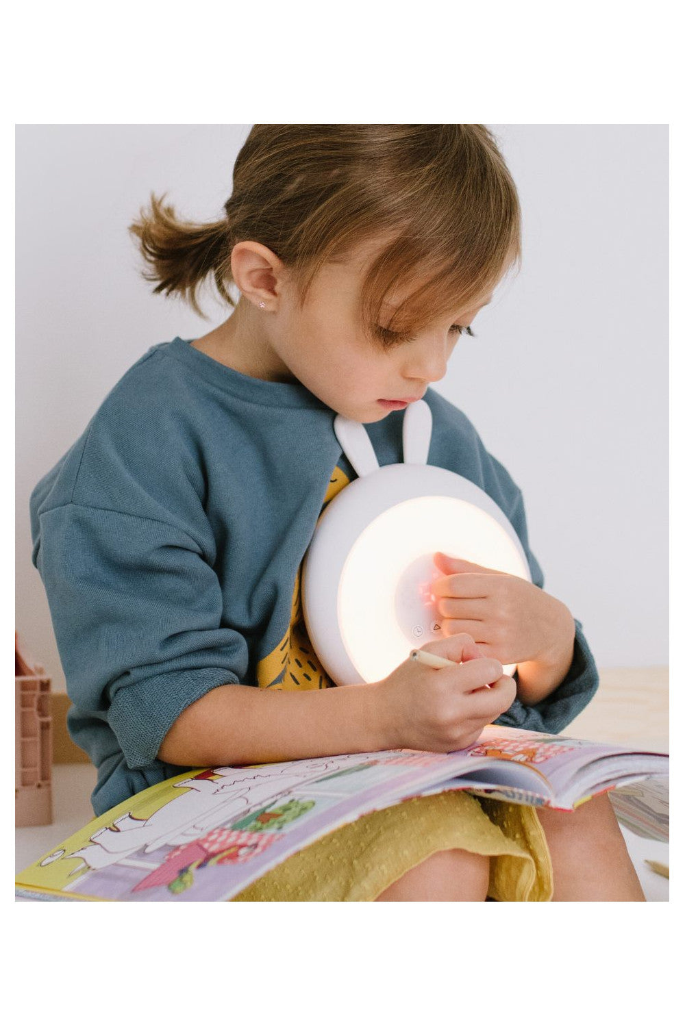 A girl holding a Rabbit Lamp with Alarm Clock – White, emitting soft light. Features sunrise and sunset functions, adjustable brightness, nature sounds, and touch control. Ideal for healthy sleep routines.