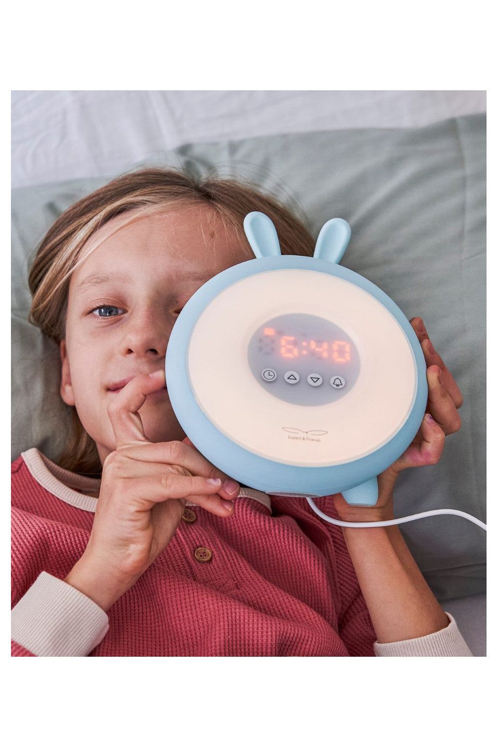 A child holding a Rabbit Lamp with Alarm Clock, featuring sunrise and sunset functions, adjustable light intensity, 5 melodies, touchpad, and non-slip base.