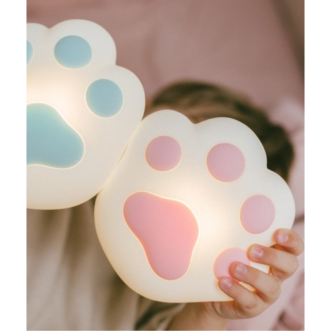 A child holds a paw-shaped light-up lamp, perfect for bedtime. Features magnet attachment, touch operation, and adjustable brightness. Ideal for a peaceful sleep environment in a children's room.