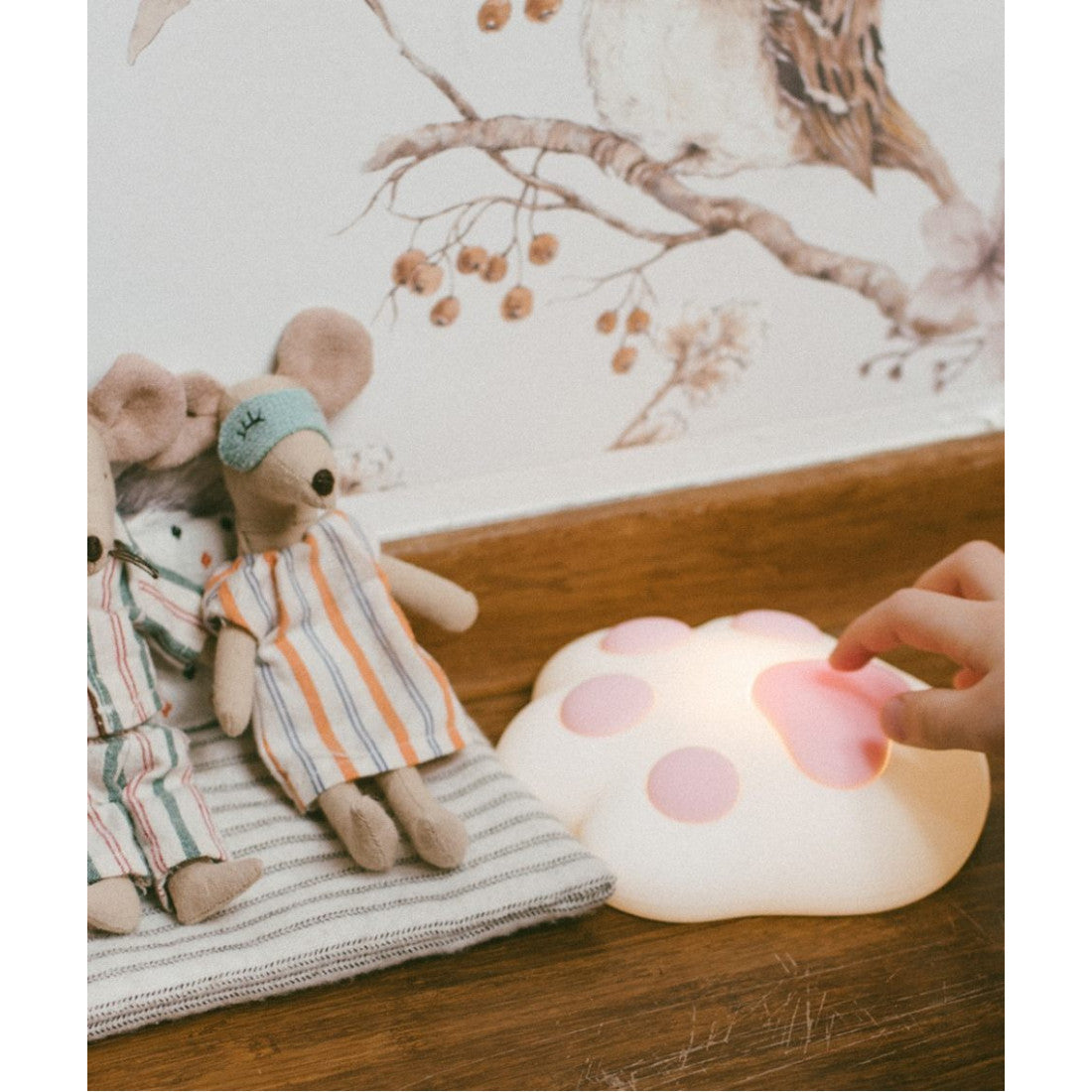 A hand pats a Paw Silicone Lamp - Pink, a toy with soft, touchable silicone. Features adjustable light, magnet, and USB charging. Ideal for children's rooms.