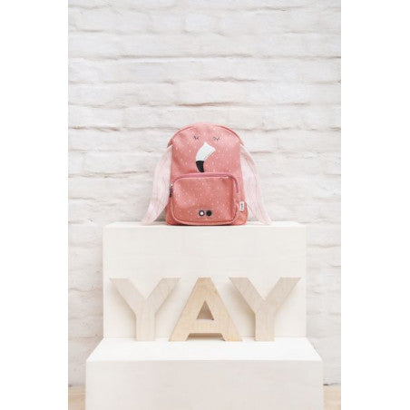 A pink Mrs. Flamingo backpack with face detail, adjustable straps, chest strap, water-repellent cotton material, big compartment, and front pocket. Dimensions: 31 x 23 x 10 cm.