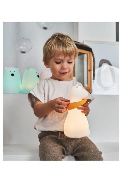 A child holds a Giraffe Silicone Lamp - White, featuring a playful giraffe shape with horns, round eyes, and a scarf. Soft, safe, and touch-responsive, perfect for bedtime companionship.