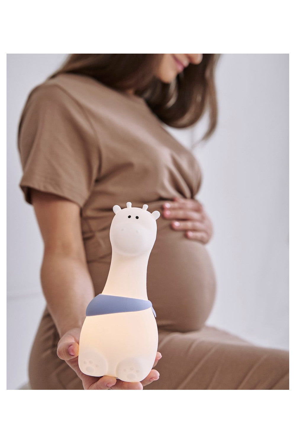 A pregnant woman holds a toy, showcasing the Giraffe Silicone Lamp - White. Child-friendly design with a giraffe shape, soft touch, color-changing light, and USB charging. Safe, playful, and perfect for bedtime.